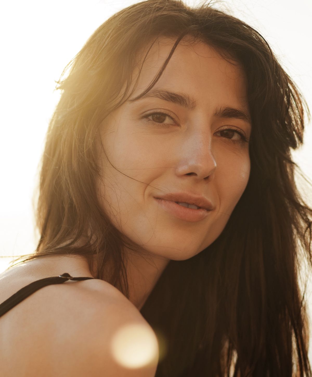 Man in white shirt seated, looking thoughtfully.