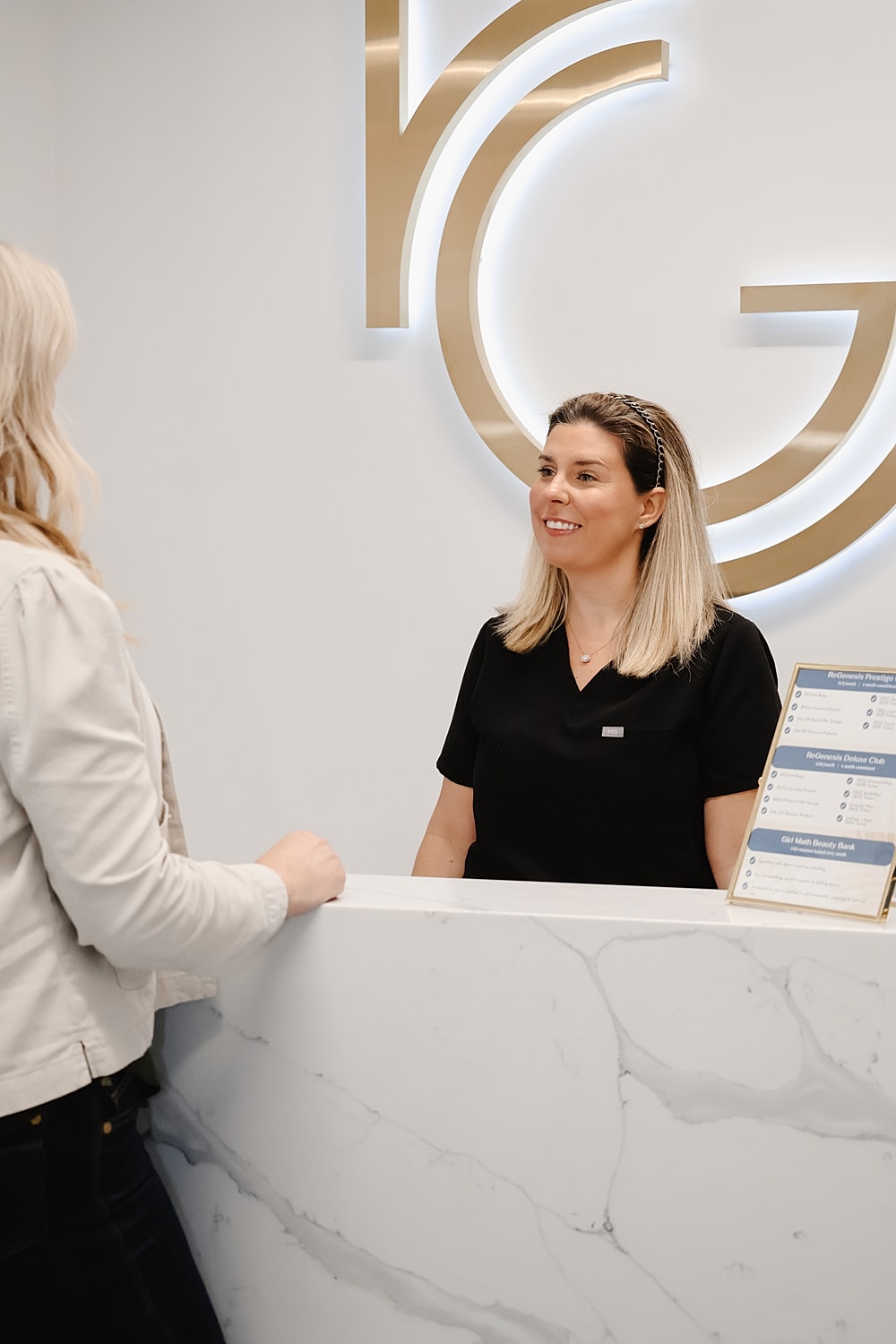 Receptionist smiling at client in beauty clinic.