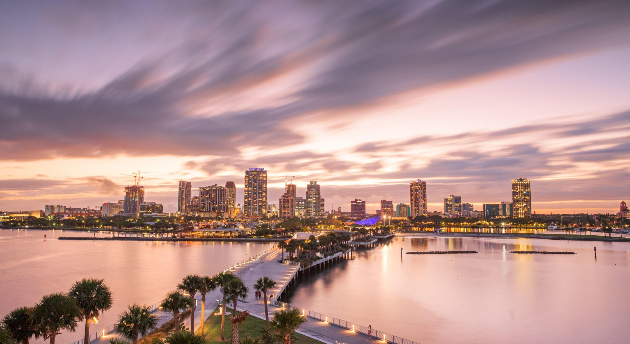 City skyline at sunset over calm water.