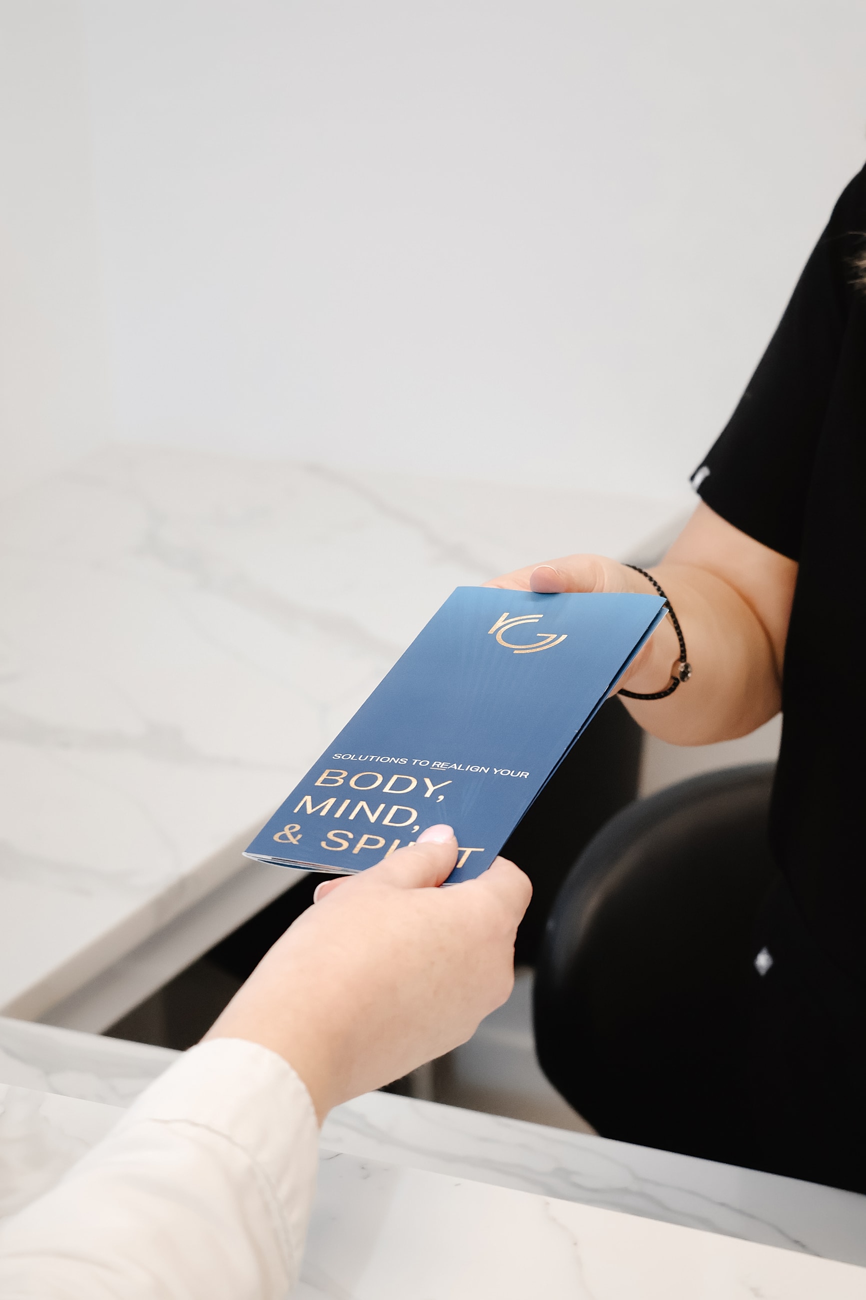 Handing over a wellness brochure at a counter.