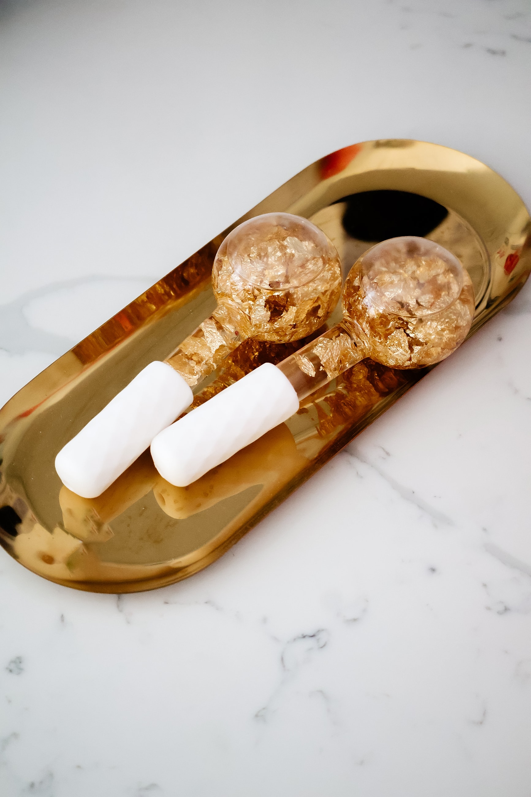 Gold leaf beauty tools on a decorative tray.