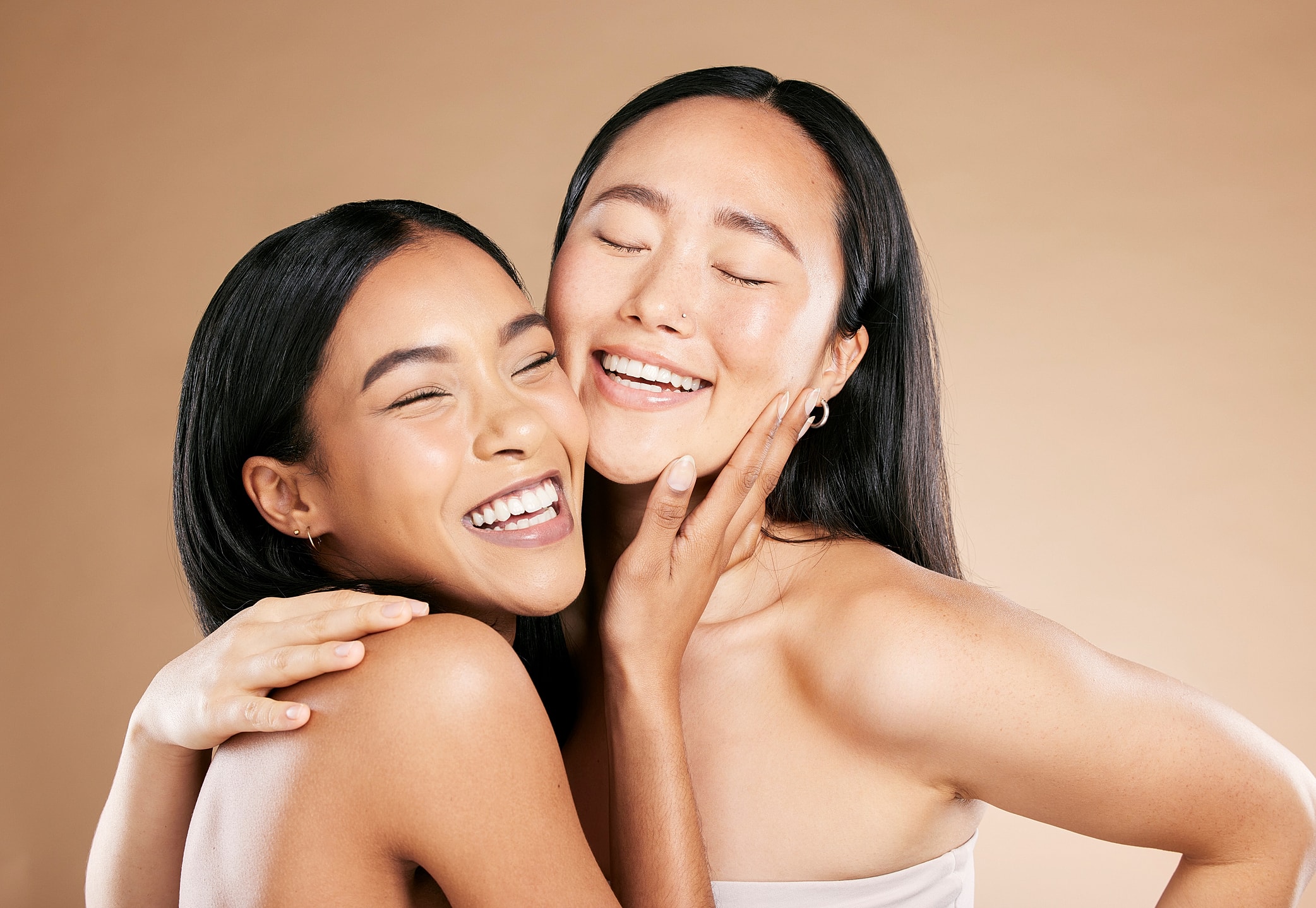 Two women laughing and embracing joyfully.