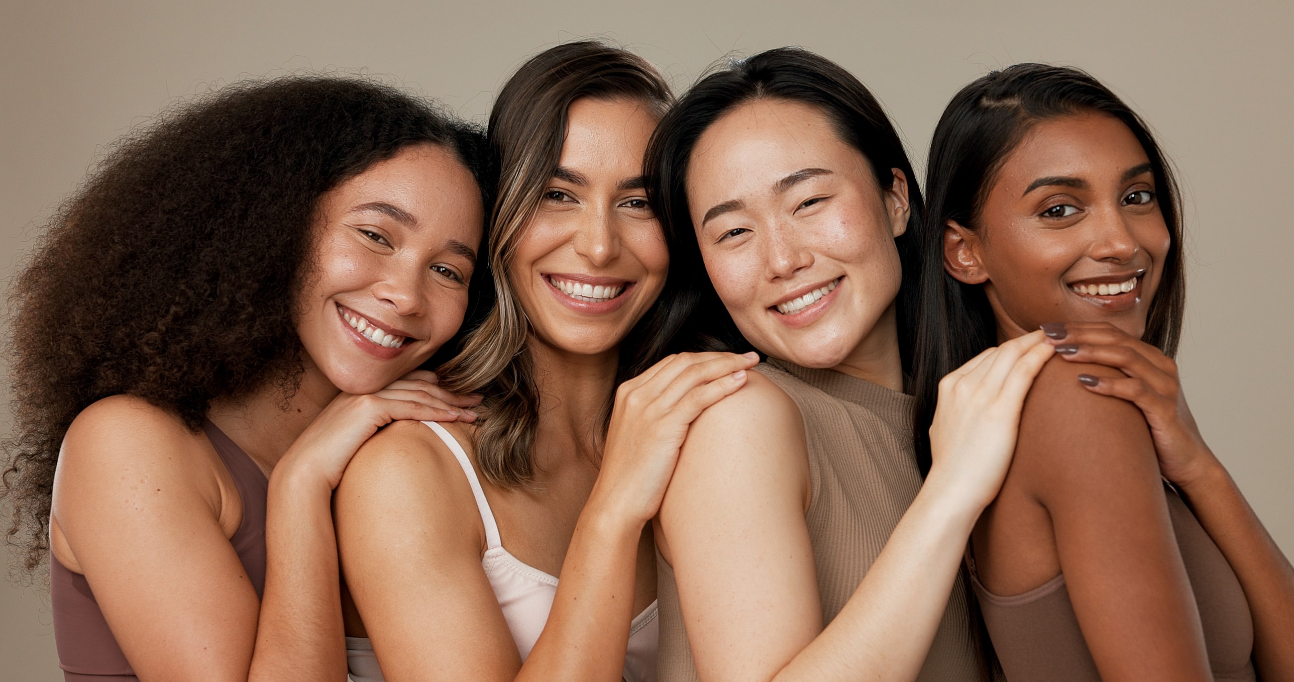 Four women smiling and embracing each other.