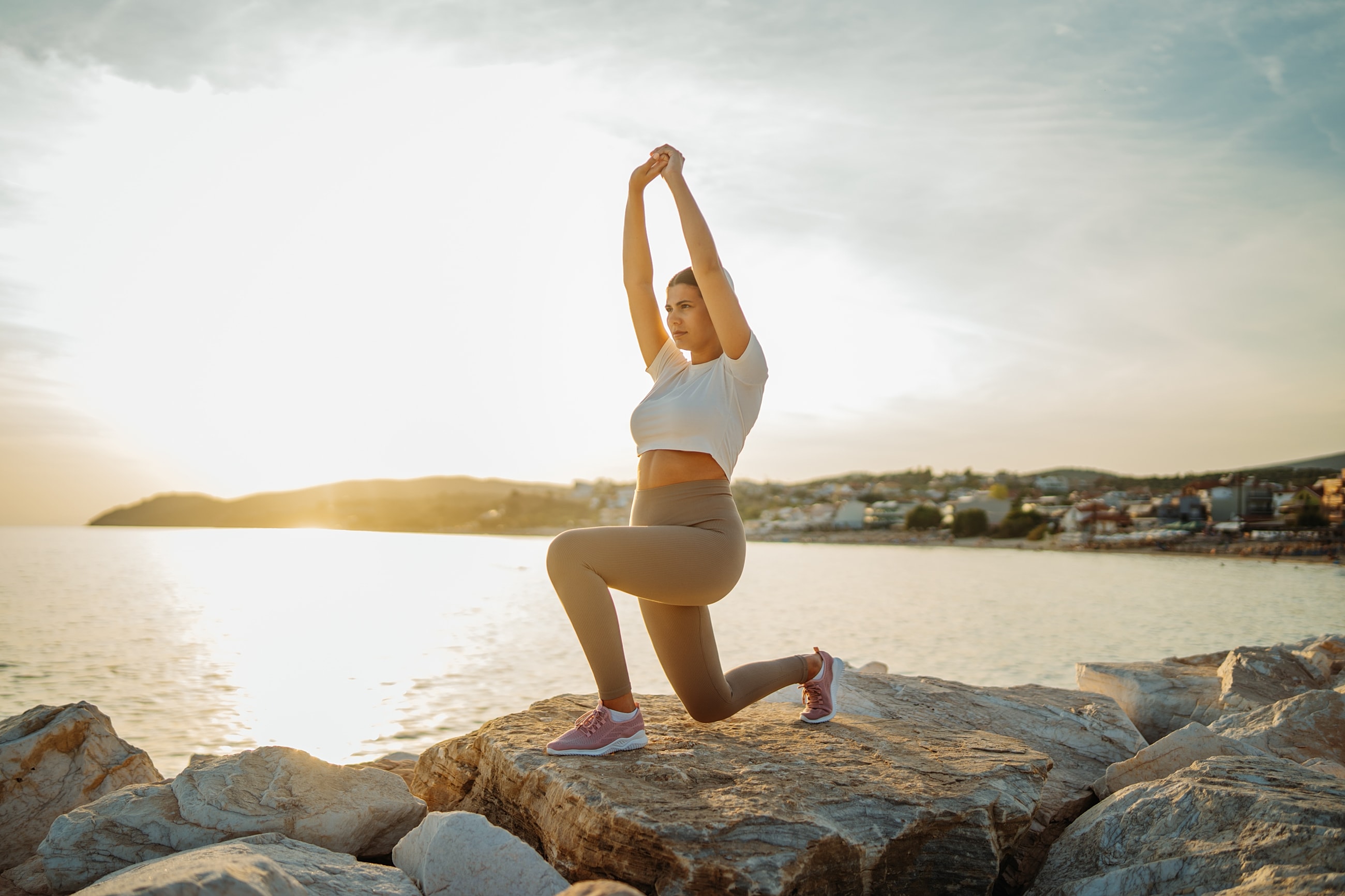 Woman exercising on rocks by the water.