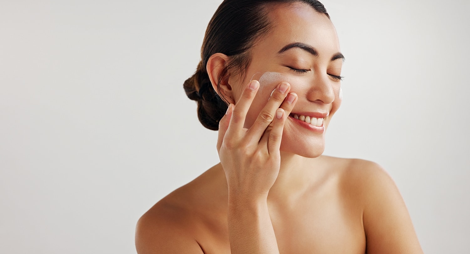 Woman cleansing her face with a gentle smile.