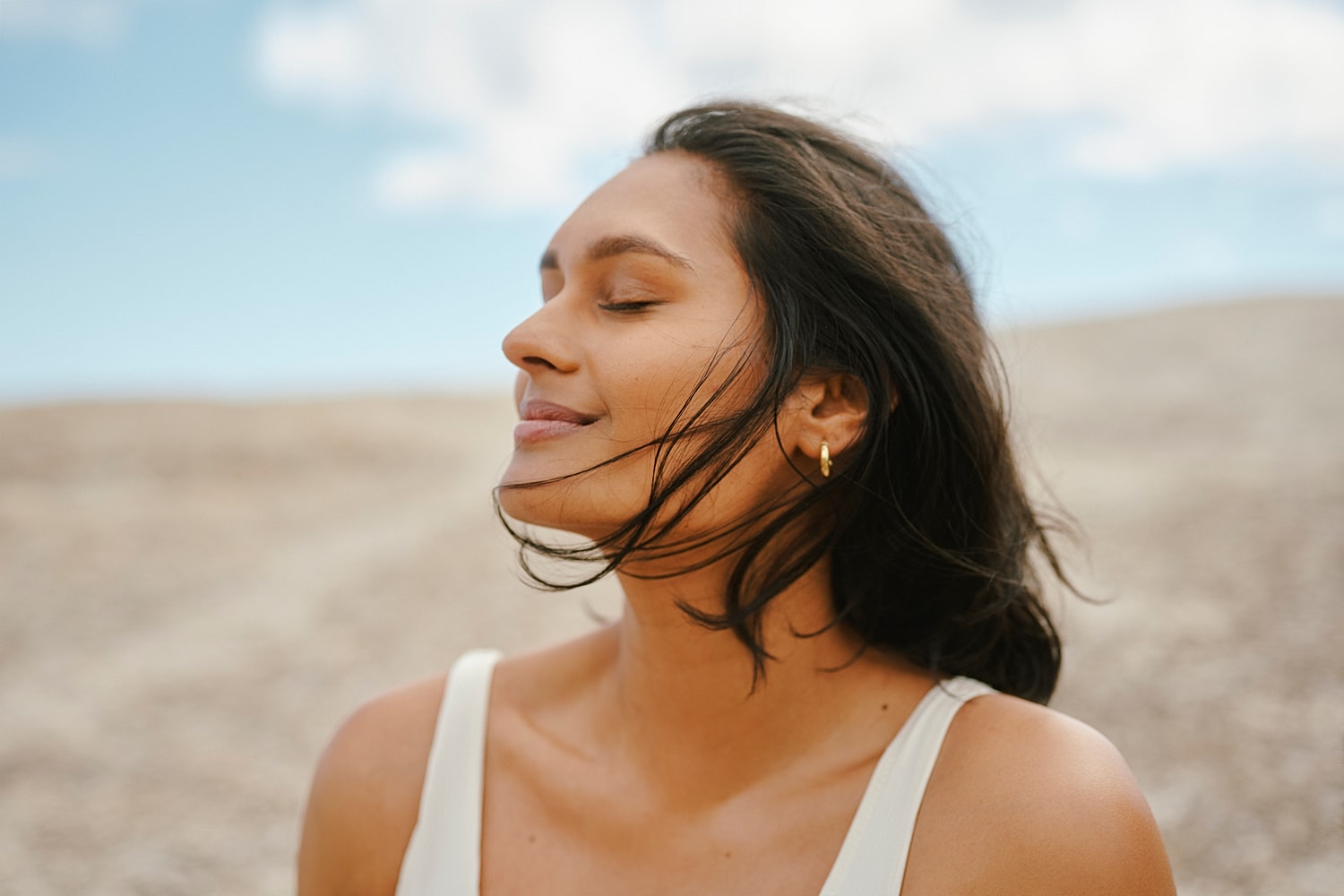 Woman enjoying the breeze outdoors, eyes closed.