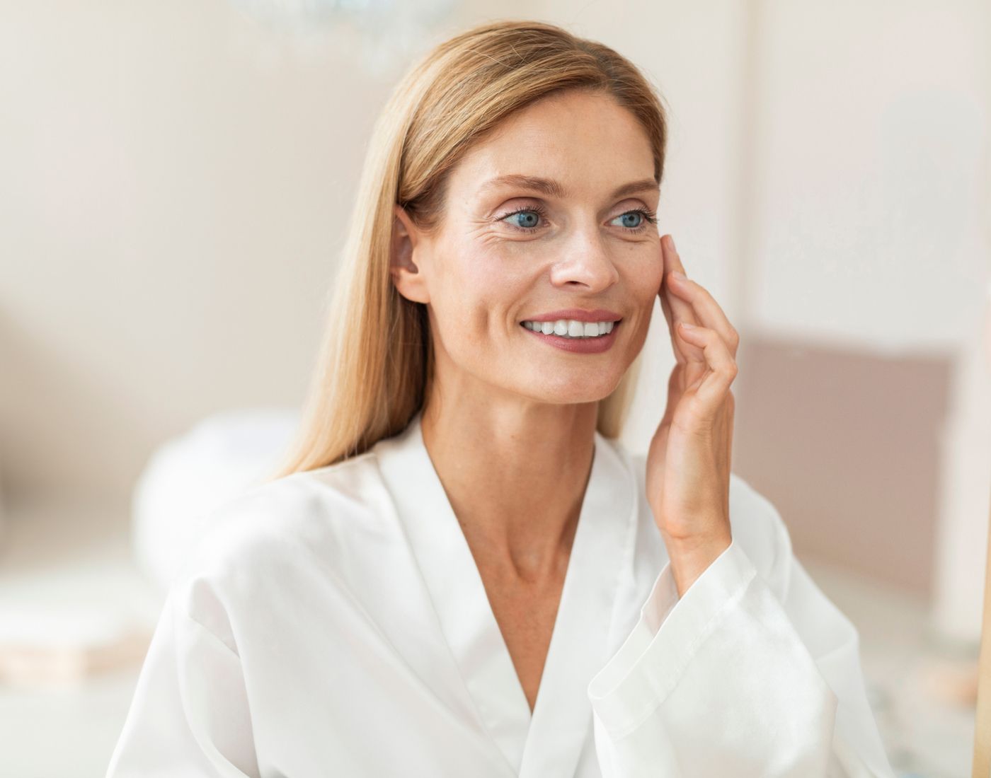 Woman applying skincare in a bright room.